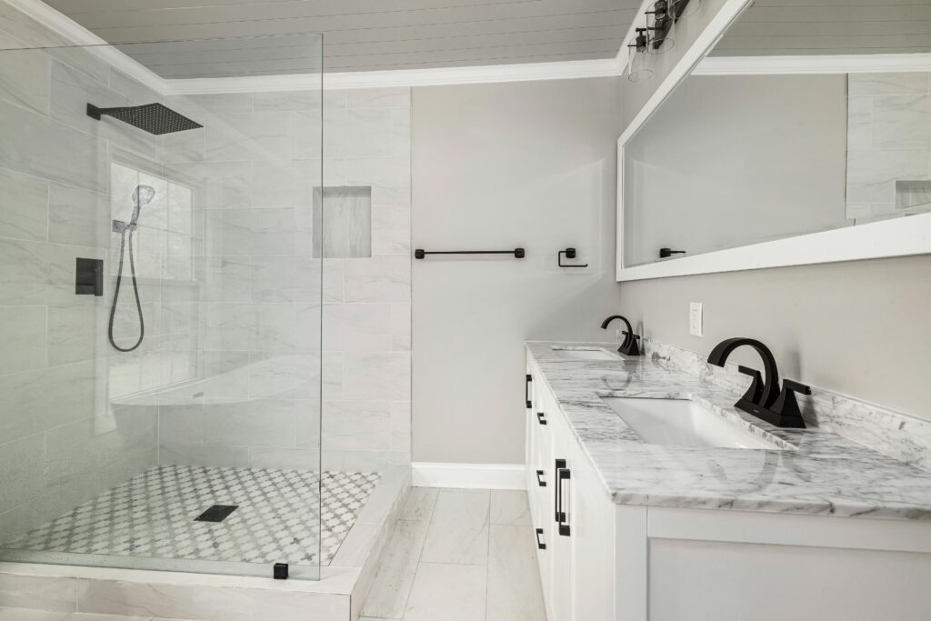 Elegant bathroom featuring dual sinks and a glass shower enclosure in a minimalist design.